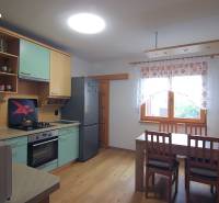 Családi ház konyhája konyhabútorral, asztallal és székekkel.