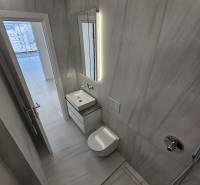 A nyaraló apartman fürdőszobája mosdóval, zuhanyzóval és ízléses világítással.