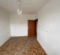 Egy üres szoba egy háromszobás lakásban világos falakkal és parkettás padlóval.