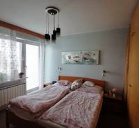Hálószoba családi házban franciaággyal, szekrénnyel és erkélyajtókkal.