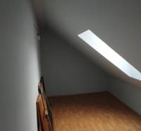 Tetőtéri szoba fa padlóval és tetőablakkal egy családi házban.