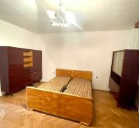 Hálószoba egy családi házban régebbi bútorokkal és fa padlóval.