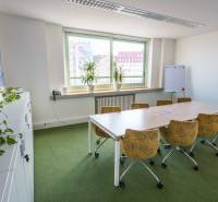 Irodák asztallal és székekkel, növényekkel és ablakkal, kilátással a városra.