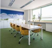 Irodák zöld szőnyeggel, sárga székekkel és nagy hegyi fotótapétával.