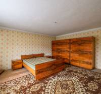 Hálószoba családi házban, fa bútorokkal és retro mintákkal a falakon.