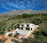 Villa Duće zölddel és hegyekkel körülvéve, háttérben kék ég.