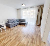 Nappali egy kétszobás lakásban kanapéval, asztallal és székekkel a fa padlón.