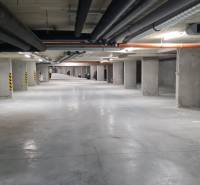 Podzemní garázs parkolóhelyekkel és beton oszlopokkal egy egyszobás lakásban.