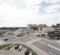 Körforgalom és környezete a Fő utcán Dunaszerdahelyen, autók mozgása, épületek, égbolt.