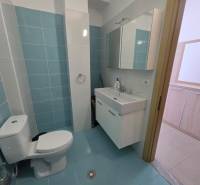 Fürdőszoba világoskék csempékkel a nyaraló apartmanban, mosdó és tükrös szekrény.