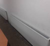 Radiátorok a raktárban és a csarnokban, a falnál betonpadlóval.