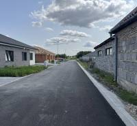 Családi házak építkezéssel és aszfaltúttal Felsővámoson felhős ég alatt.