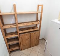 Fa polcok a hűtőszekrény és a mikrohullámú sütő mellett egy kétszobás lakásban.