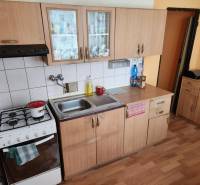 Konyha egy egyszobás lakásban fa szekrényekkel és gáz tűzhellyel.
