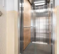 Modern lift kinyitása egy lakóház emeletén fa dekorációval.