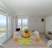 Nyaraló apartman nagy asztallal, tengerre néző kilátással, gyümölcsökkel és pohár gyümölcslével.