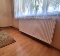 Szoba radiátorral az ablak alatt és függönnyel a családi házban.
