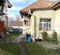 Családi ház a Partizánska utcában, Detván, udvarral, növényekkel és vízelvezető csövekkel.