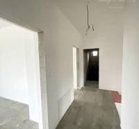 Folyosó egy családi házban fehér falakkal és beton padlóval.