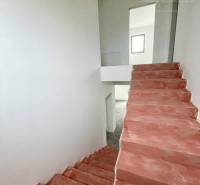 A családi házban betonlépcsők és fehér falak vezetnek a felső emeletre.