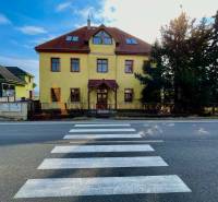 Az épület a Chrabrany utcában, Topoľčanyban, a gyalogátkelőhellyel és a fákkal szemben.