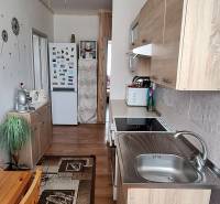 Konyha egy háromszobás lakásban fa bútorokkal és mennyezeti ventilátorral.