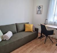 Nappali egy háromszobás lakásban kanapéval, íróasztallal és székkel.