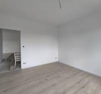 Üres szoba fehér falakkal és világos fa padlóval egy családi házban.