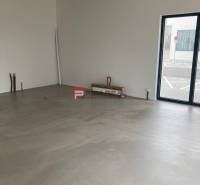 Üzlethelyiségek nagy ablakokkal és betonpadlóval.