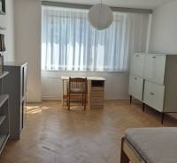 Kétszobás lakásban lévő fa padló ággyal, íróasztallal és szekrényekkel.