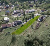 Légi felvétel Raková község lakóterületeiről, zöld domboldalak és házak.