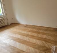 Üres szoba egy háromszobás lakásban parkettás padlóval és ablakkal.