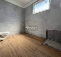 Fürdőszoba egy családi házban csempével és szabadon álló WC-vel, befejezésre vár.