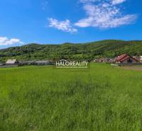 Zöldterület és panoráma Udičában, lakóterületek házakkal és erdős dombokkal a háttérben.