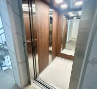 Nyitott lift egy 3 szobás lakásban fa burkolattal és világítással.