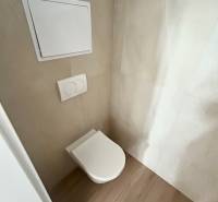 WC rejtett öblítéssel egy 3 szobás lakásban, világos csempékkel és fa padlóval körülvéve.