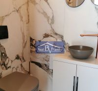 Fürdőszoba egy kétszobás lakásban márványburkolattal, szekrénnyel és mosdóval.