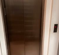 Rozsdamentes acél lift az irodában, fa mintázatú padlóval.
