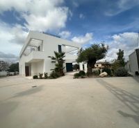 Villa Benissében minimalista építészet és gondozott kert a kék ég alatt.