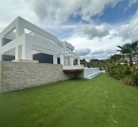 Villa Benissében kerttel és kőfallal a kék ég alatt.