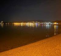 Éjszakai strand Vodice városában, Horvátország, a városi fények tükröződésével a vízen.