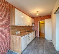 A háromszobás lakás konyhája téglaburkolattal és fa dekor padlóval.