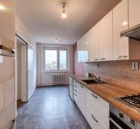 Konyha egy háromszobás lakásban fa dekor padlóval és nagy ablakkal.