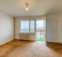 Nappali egy háromszobás lakásban, szőnyeggel, radiátorral és erkéllyel.