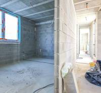 Egy építés alatt álló családi ház belső tere betonfalakkal és nagy ablakokkal.