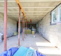 Családi ház építése Hontianske Tesáre-ban vakolatlan falakkal és tartóoszlopokkal.