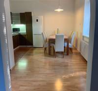 Étkező sarok fa dekor padlóval egy kétszobás lakásban, asztal és négy szék.