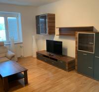 Nappali egy kétszobás lakásban fa dekor padlóval és televízióval.