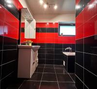 Fekete-piros fürdőszoba családi házban tükörrel és káddal, feltűnő csempekombináció.