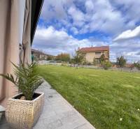 A Lipová utcai családi ház kertje Dubovában, gyepes területtel és kövezett járdával.